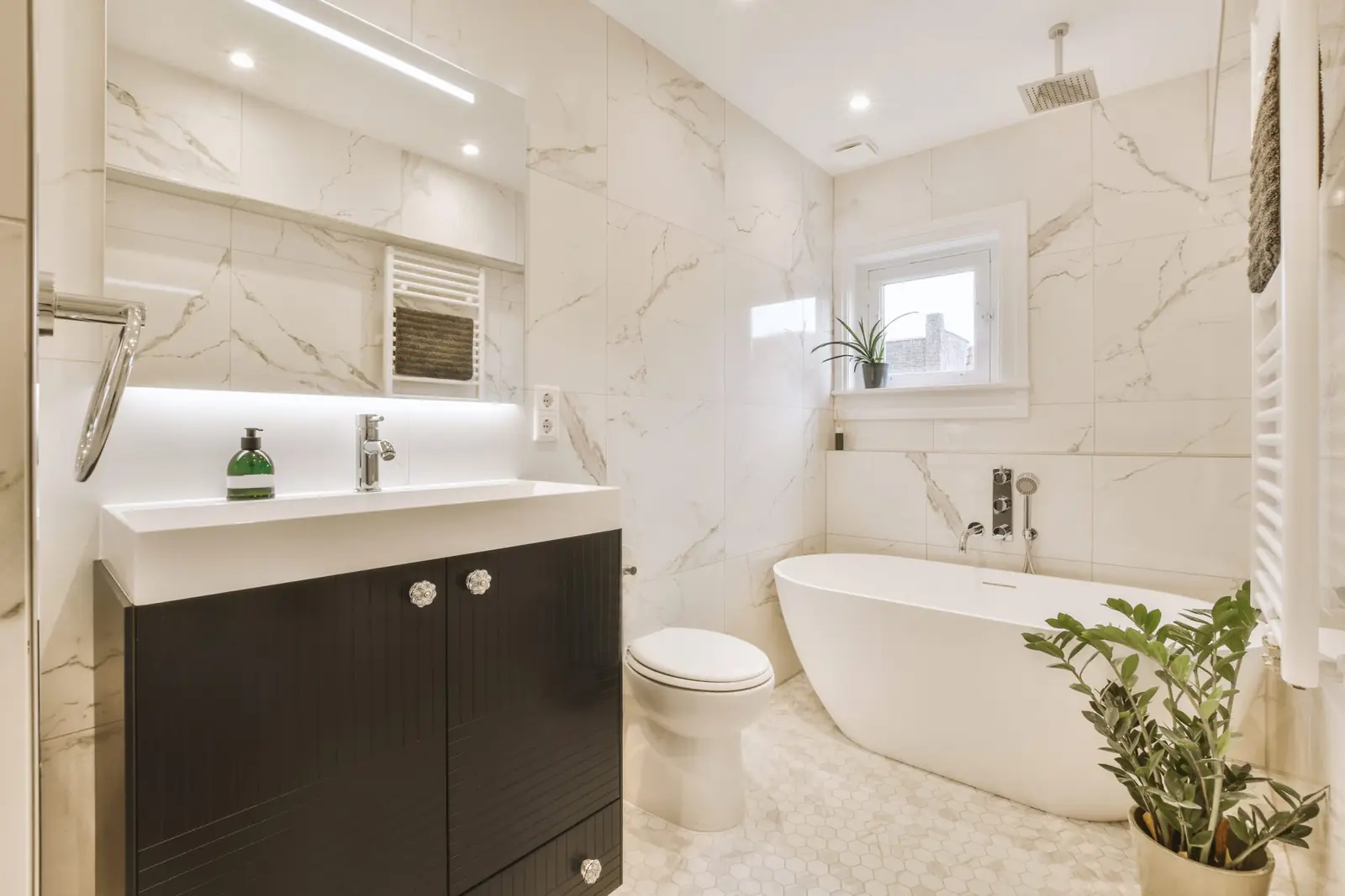 A marble bathroom with a freestanding tub and a dark vanity