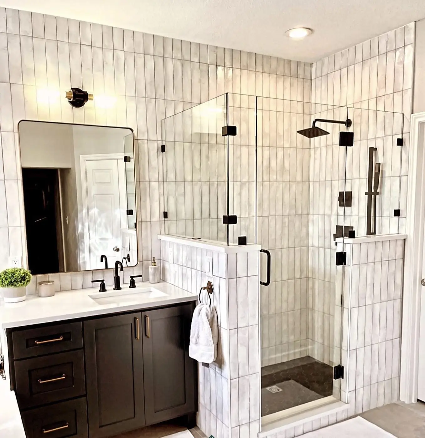 A bathroom with white vertical wall tile and a dark shaker vanity
