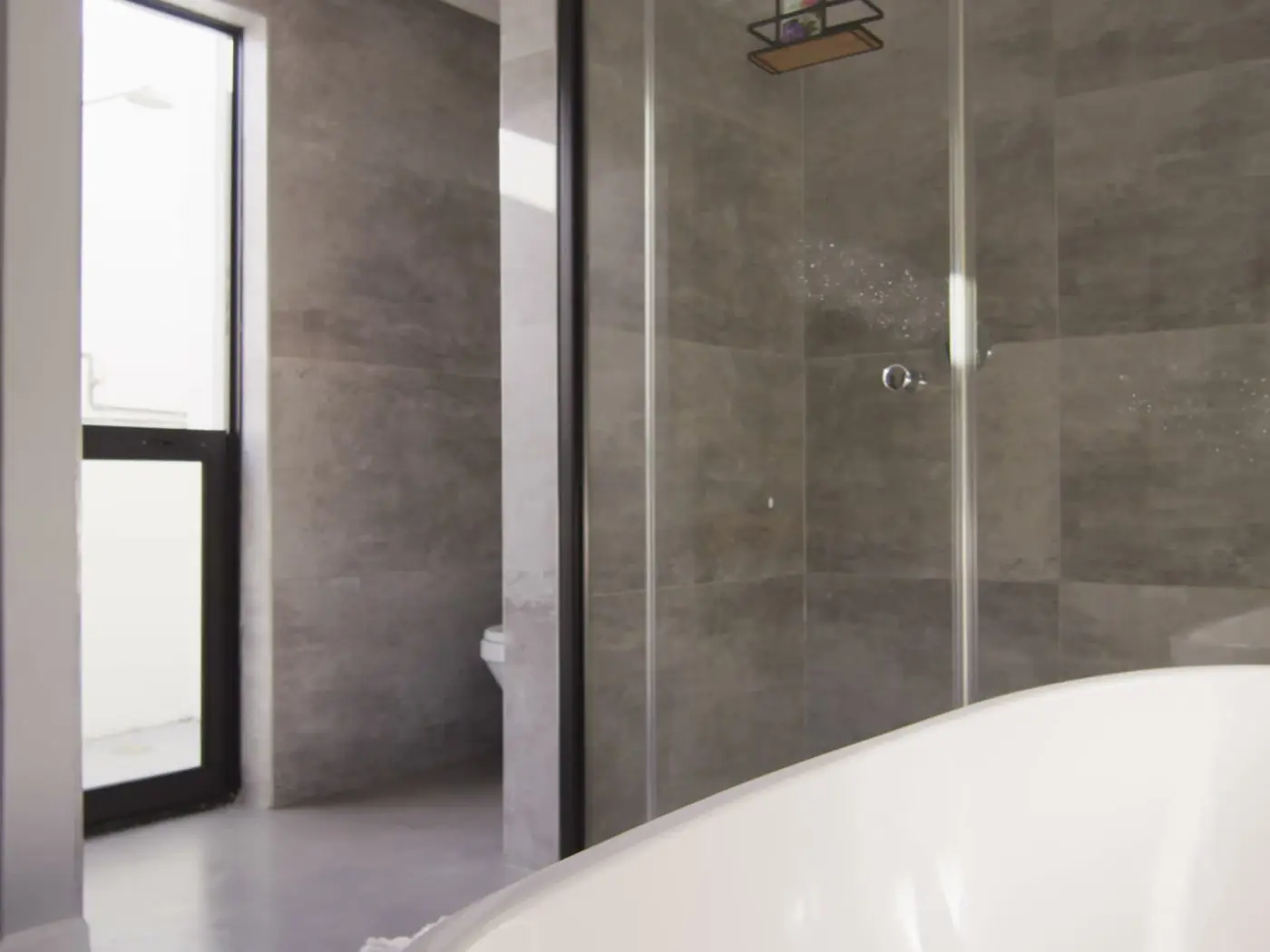 A stone-tiled bathroom with a glass shower panel
