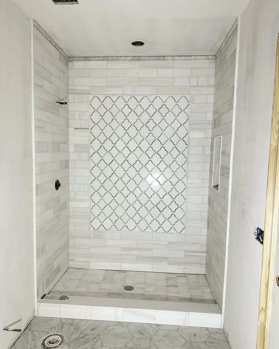 A white tiled shower with a tall arabesque mosaic feature panel