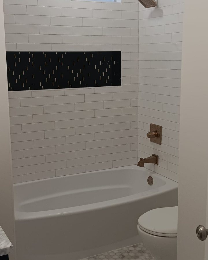 White subway tile tub and shower surround with a dark textured accent band