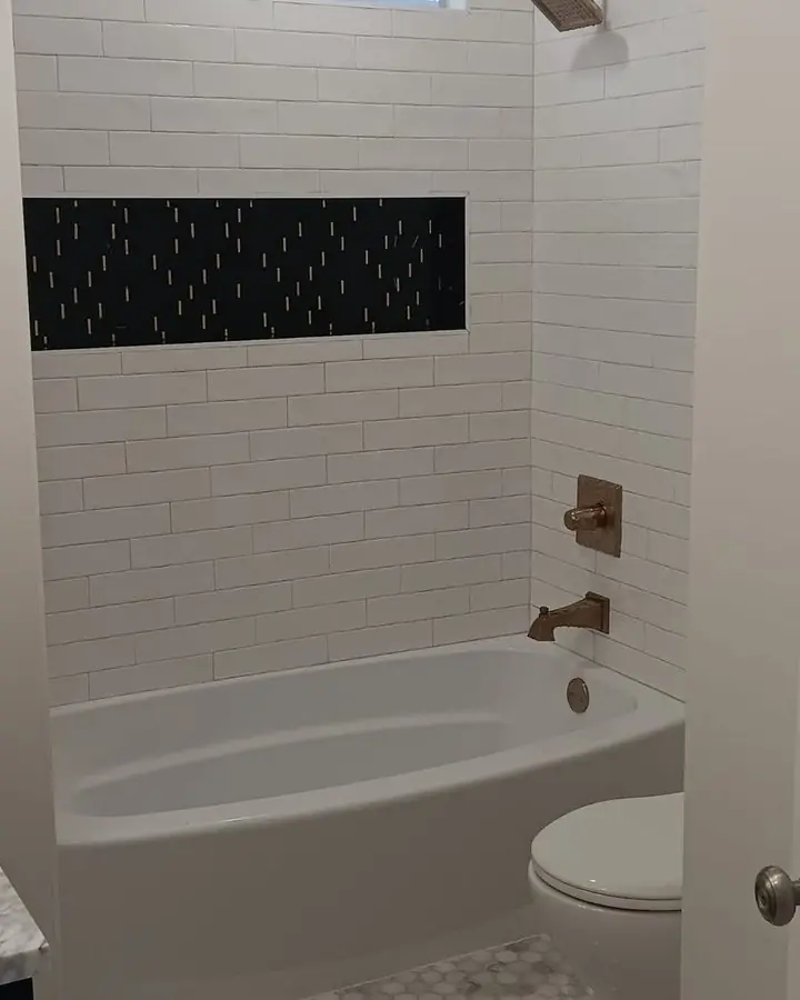 White subway tile tub and shower surround with a dark textured accent band