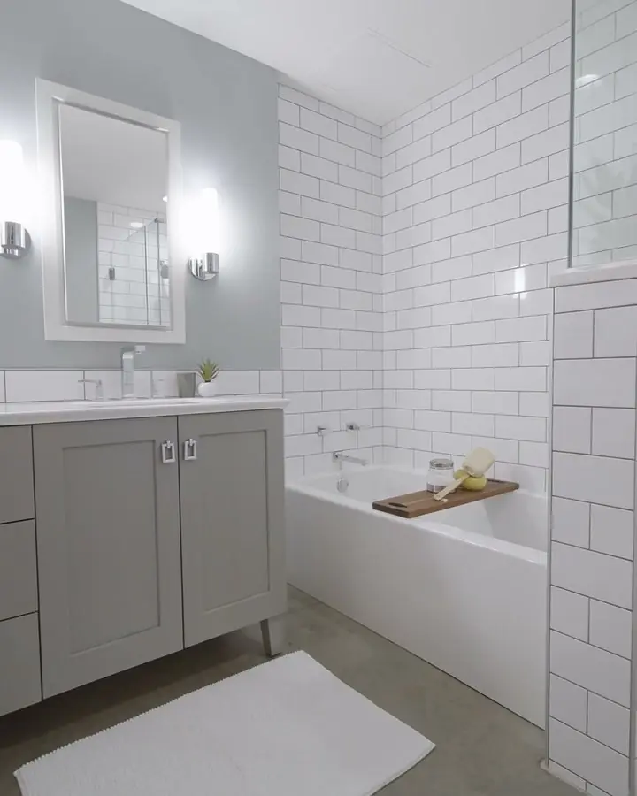Low-profile shower base set into a white subway tiled shower beside a gray vanity