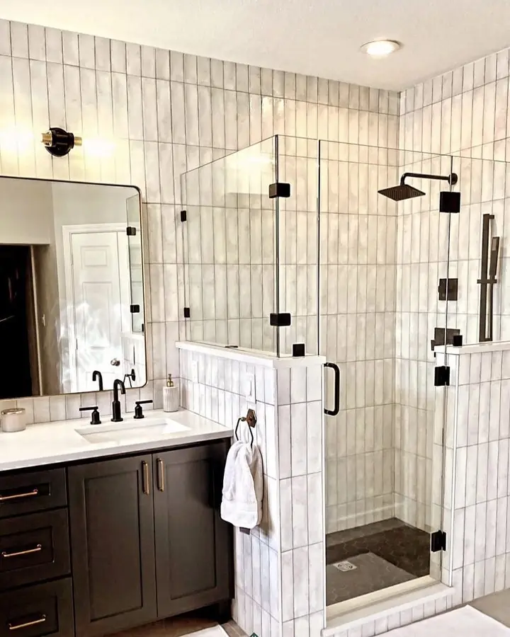 Frameless glass shower enclosure against white vertical wall tile with matte black fixtures