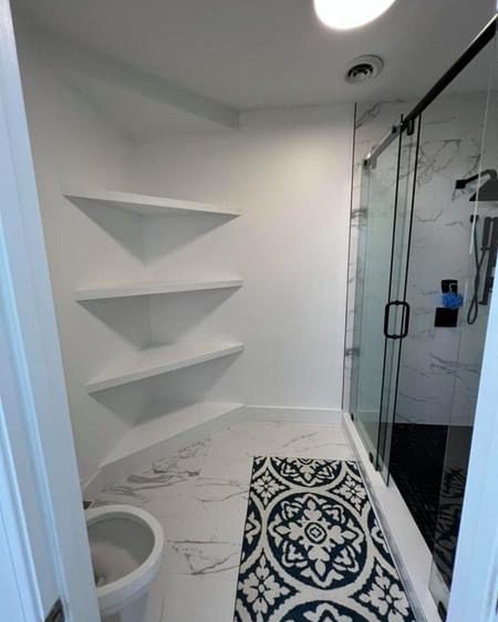 Stone-tiled shower wall behind a clear glass panel next to a white freestanding tub