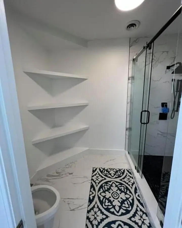 Stone-tiled shower wall behind a clear glass panel next to a white freestanding tub