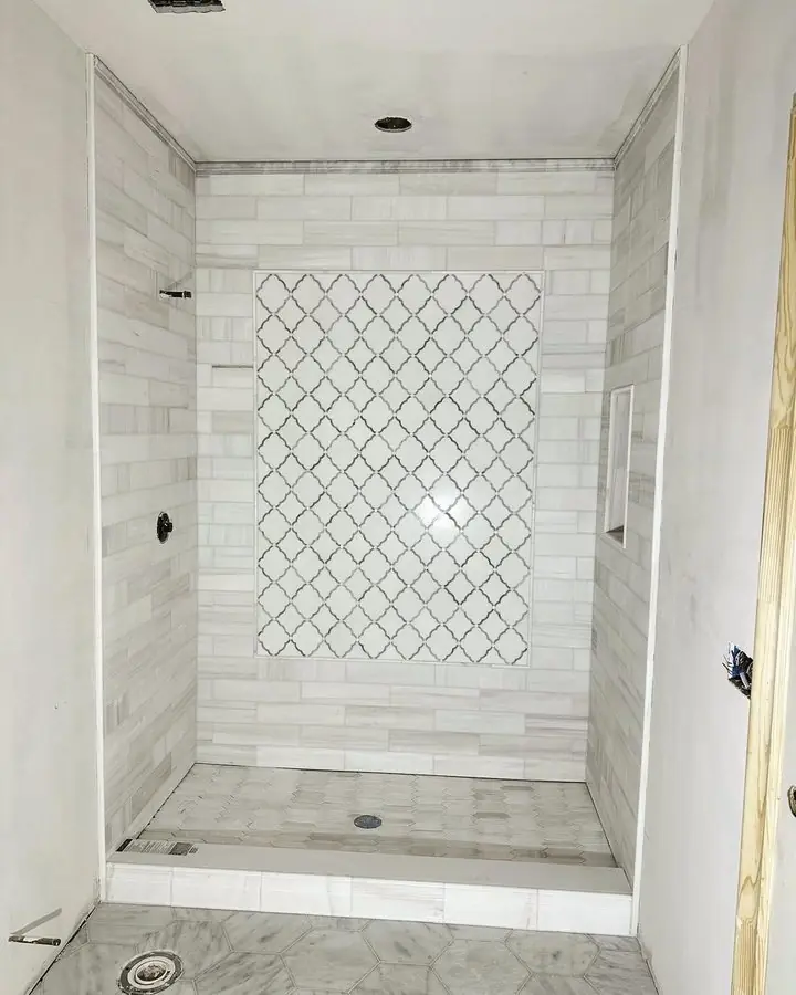 White tiled shower with a tall arabesque mosaic feature panel set into the back wall