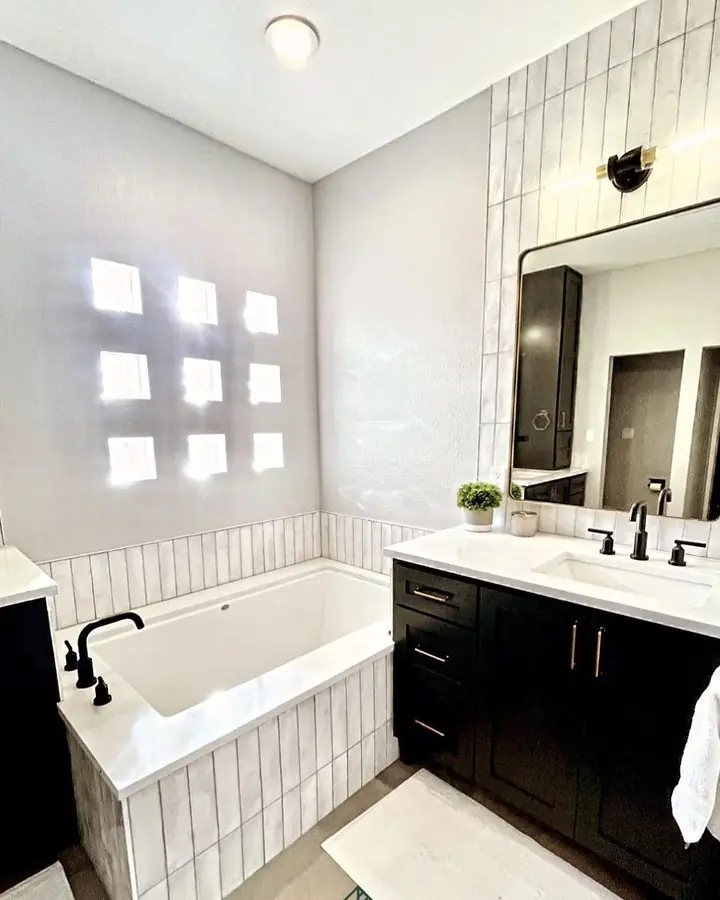 Marble bathroom with a pendant light over a built-in tub and a dark timber window frame