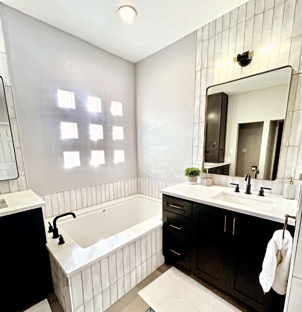 Renovated bathroom with a tiled bathtub surround, glass block window and a dark timber vanity