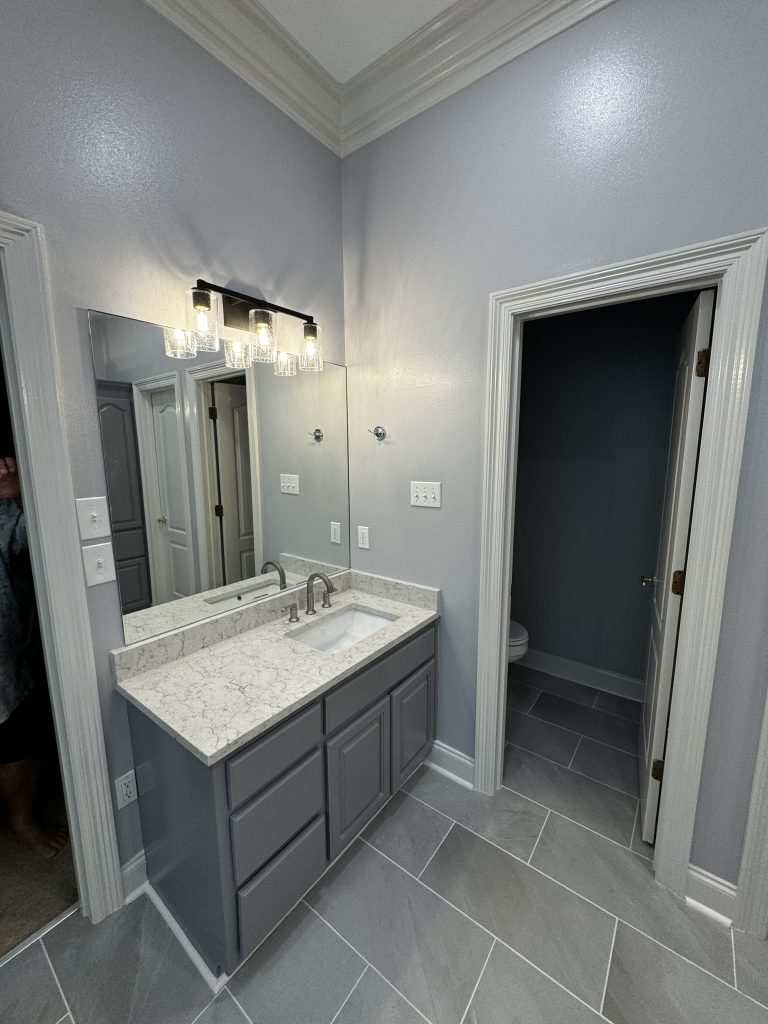 Renovated bathroom with a grey double vanity, marble top and large-format grey floor tile