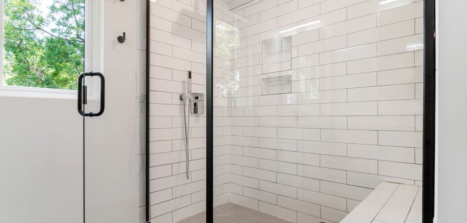 Black-framed glass shower enclosure with white subway tile