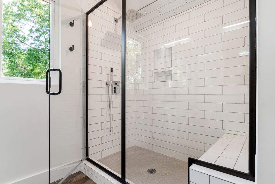 Black-framed glass shower enclosure with white subway tile