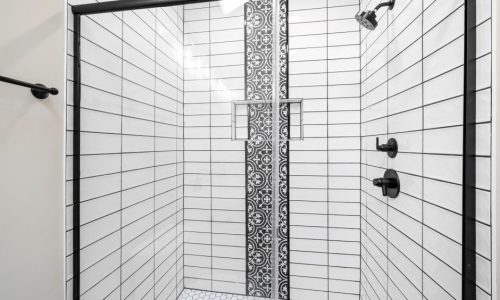 White subway tile shower with a decorative patterned accent strip
