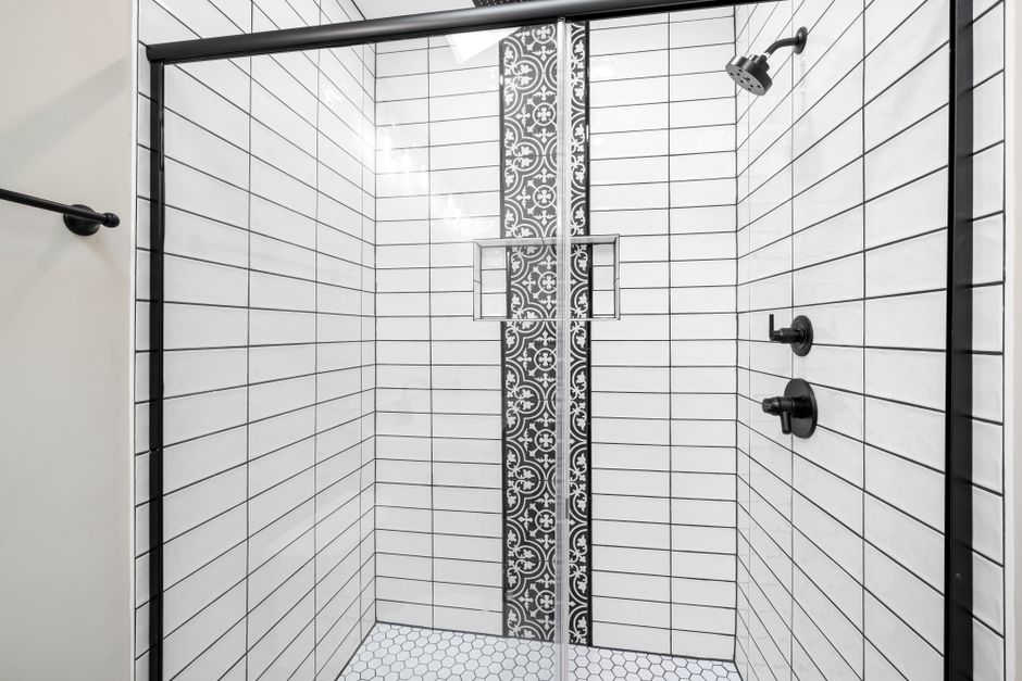 White subway tile shower with a decorative patterned accent strip