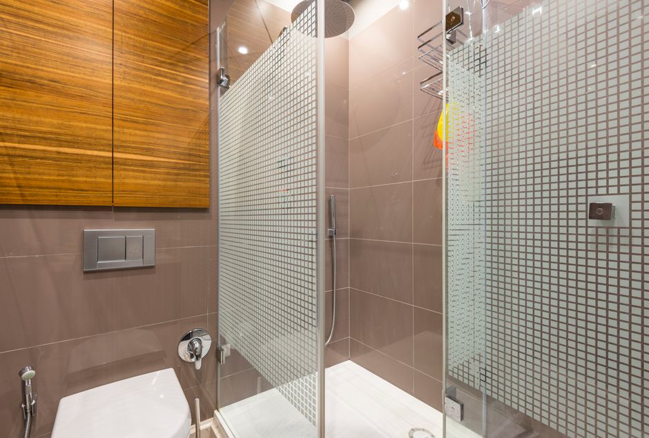 Modern glass-enclosed walk-in shower with mosaic accent tile in a small bathroom